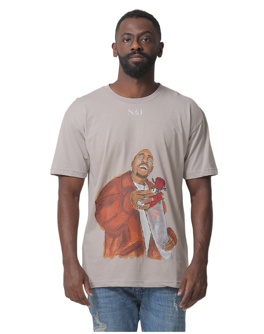 A man wearing a brown T-shirt with an illustration of 2Pac holding a rose on the front.